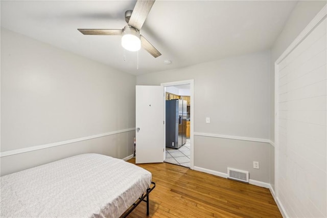 bedroom featuring stainless steel refrigerator with ice dispenser, ceiling fan, and hardwood / wood-style floors