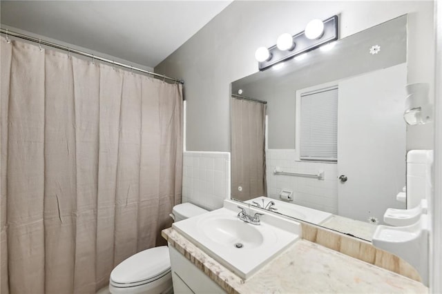 bathroom featuring vanity, tile walls, and toilet