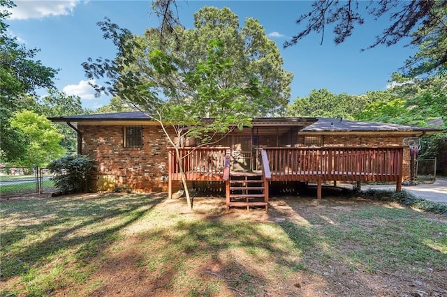 rear view of house featuring a deck and a lawn