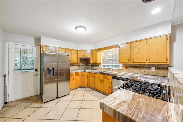 kitchen with backsplash, stainless steel appliances, sink, and light tile patterned flooring