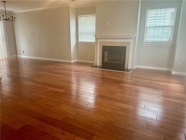 unfurnished living room with hardwood / wood-style flooring, crown molding, and a wealth of natural light