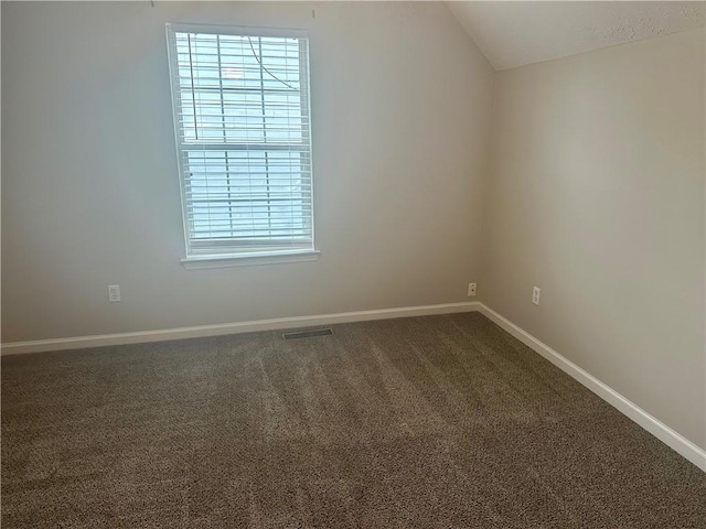 empty room with vaulted ceiling and carpet flooring