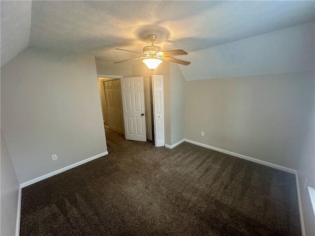 bonus room featuring dark colored carpet, lofted ceiling, a textured ceiling, and ceiling fan