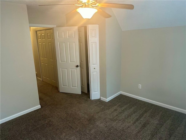 unfurnished bedroom with ceiling fan, a closet, vaulted ceiling, and dark carpet