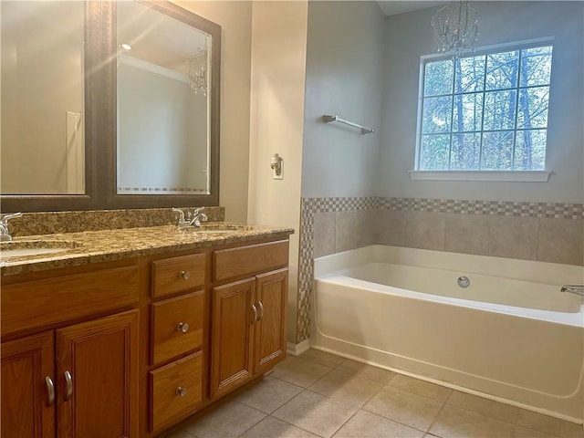 bathroom featuring an inviting chandelier, a tub to relax in, vanity, and tile patterned flooring