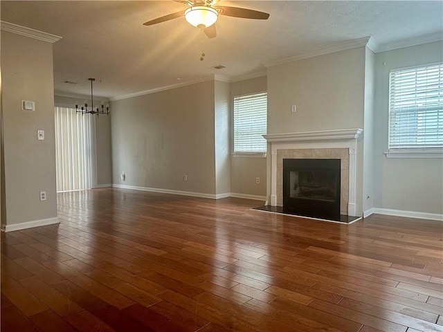 unfurnished living room featuring dark hardwood / wood-style flooring, ceiling fan with notable chandelier, crown molding, and a fireplace