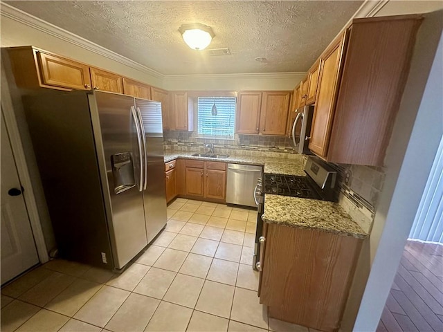 kitchen with backsplash, light stone counters, crown molding, and stainless steel appliances