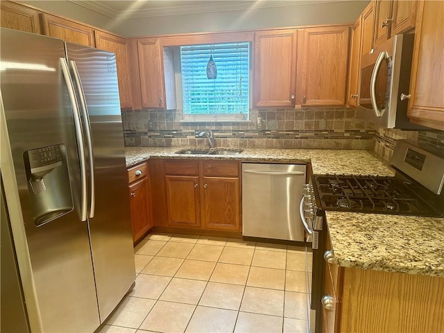 kitchen with ornamental molding, backsplash, appliances with stainless steel finishes, light stone countertops, and sink