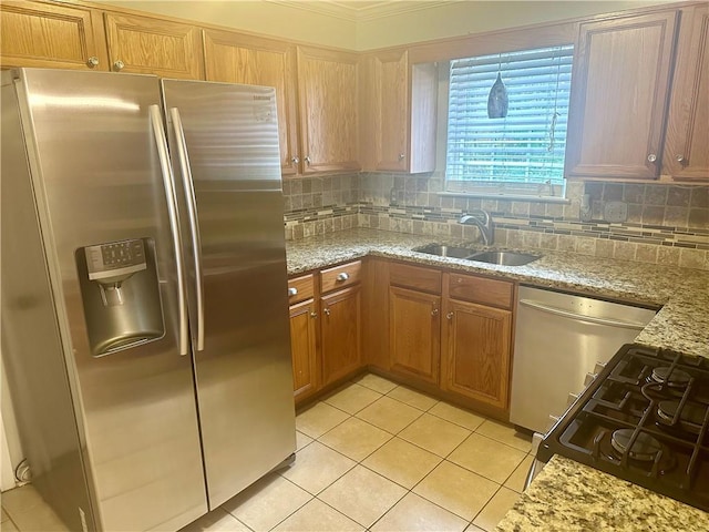 kitchen featuring light stone counters, crown molding, stainless steel appliances, light tile patterned floors, and sink