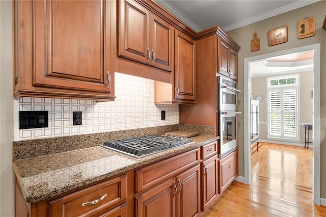 kitchen with brown cabinets, stainless steel appliances, backsplash, and light wood-style floors