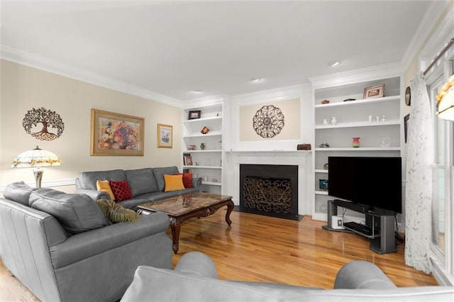 living area with a fireplace with flush hearth, ornamental molding, built in features, and light wood-style floors