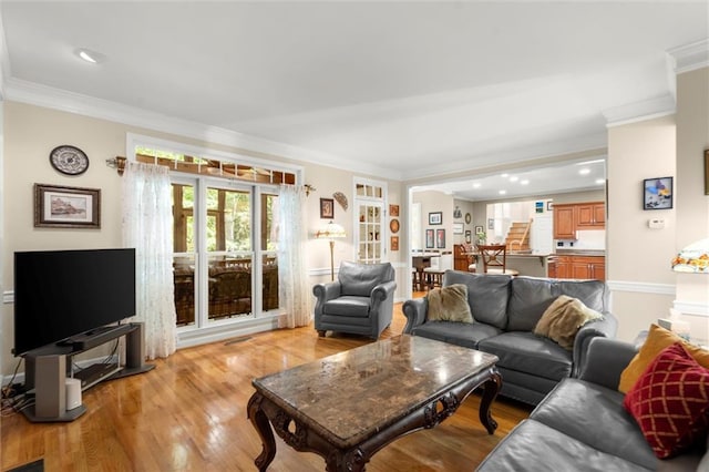 living area with light wood-style floors, ornamental molding, baseboards, and recessed lighting