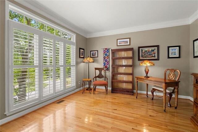 living area with baseboards, visible vents, ornamental molding, and light wood finished floors