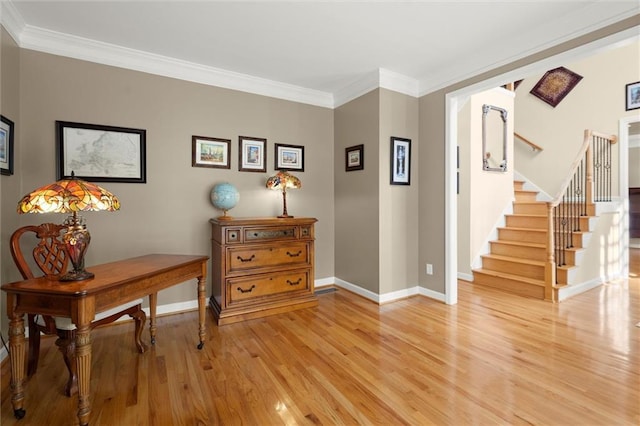 interior space featuring baseboards, ornamental molding, light wood finished floors, and stairs