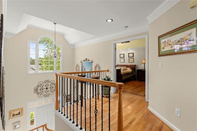 hallway with crown molding, a chandelier, an upstairs landing, and light wood-style flooring