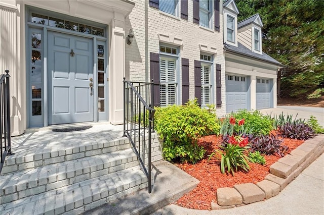 entrance to property with brick siding, an attached garage, and driveway