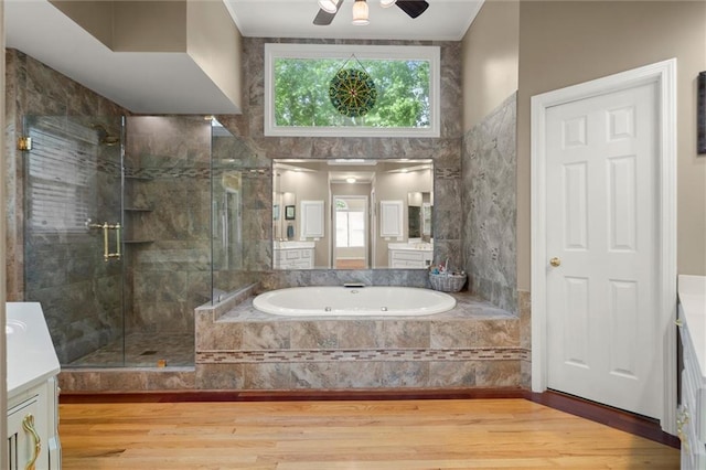bathroom featuring a stall shower, wood finished floors, a bath, and vanity