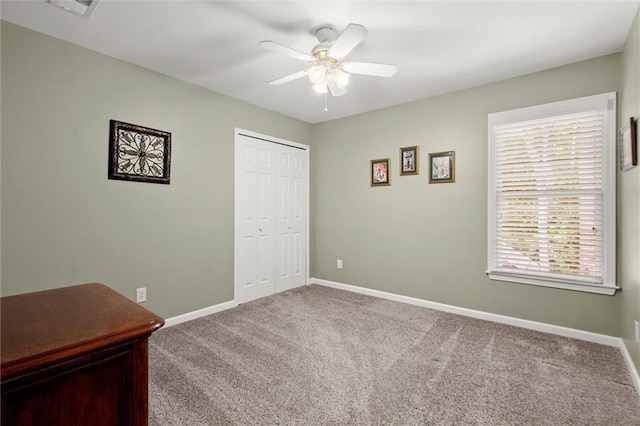 unfurnished bedroom with a closet, carpet flooring, baseboards, and ceiling fan