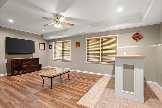 living area with baseboards, ornamental molding, ceiling fan, and wood finished floors
