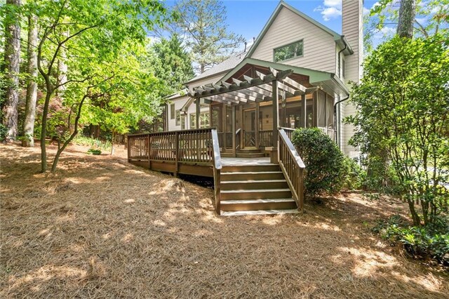 back of property featuring stairs, a pergola, a sunroom, a deck, and a chimney