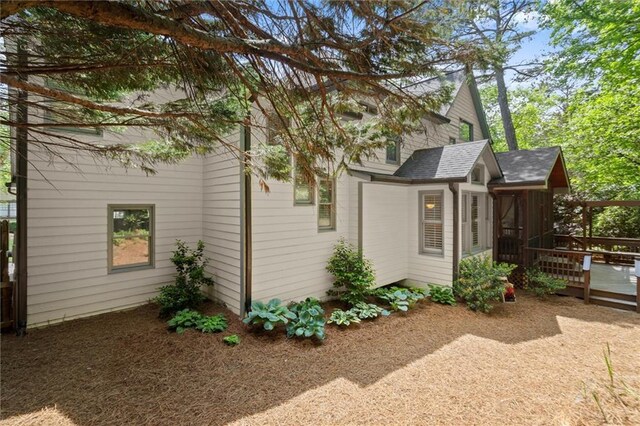 view of side of property featuring roof with shingles and a deck