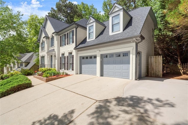 colonial inspired home with fence, a shingled roof, an attached garage, and driveway