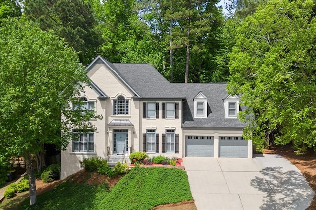colonial home featuring a garage, roof with shingles, and driveway
