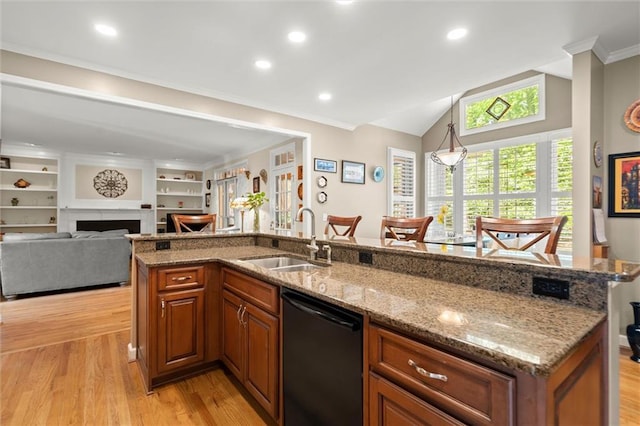 kitchen featuring brown cabinetry, a sink, dishwashing machine, and light wood-style floors