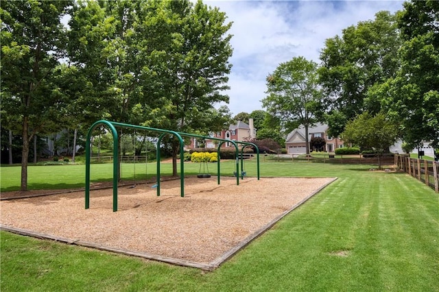 view of property's community featuring a lawn, fence, and playground community
