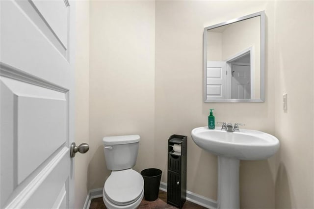 bathroom with baseboards, a sink, and toilet