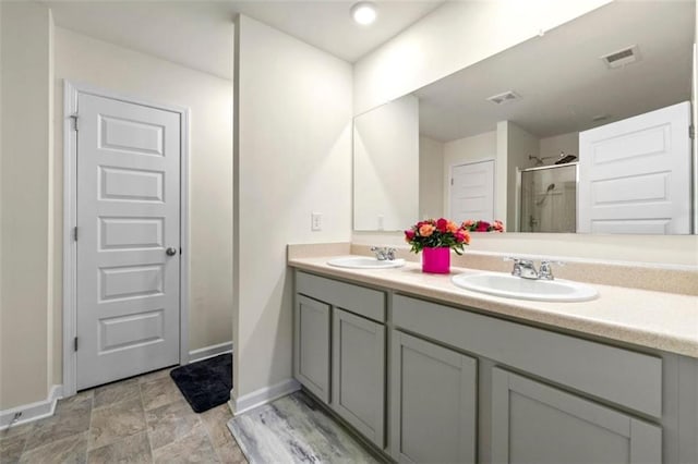 full bath featuring double vanity, a sink, visible vents, and baseboards