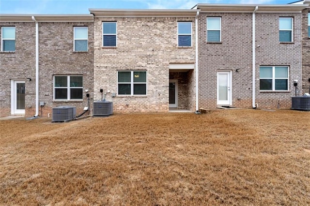 back of house featuring brick siding, a yard, and central AC unit