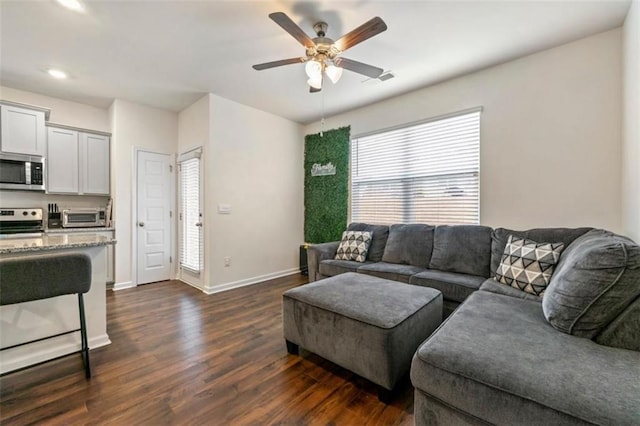 living area featuring a toaster, visible vents, baseboards, a ceiling fan, and dark wood-type flooring