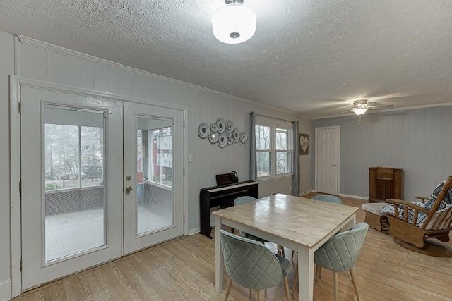 dining room with crown molding, a textured ceiling, light wood-type flooring, and french doors