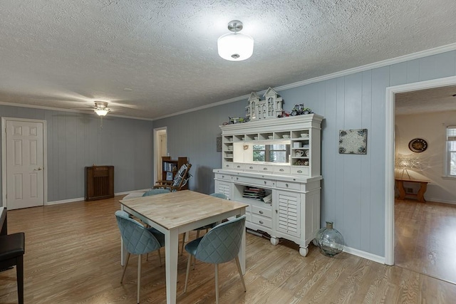 dining area with ornamental molding, a textured ceiling, and light wood-type flooring