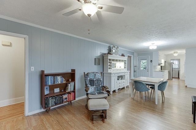 interior space featuring ceiling fan, ornamental molding, light hardwood / wood-style floors, and a textured ceiling