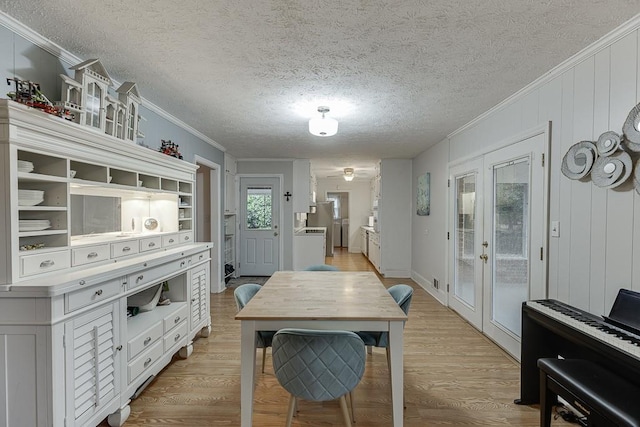 dining area with crown molding, french doors, a textured ceiling, and light wood-type flooring