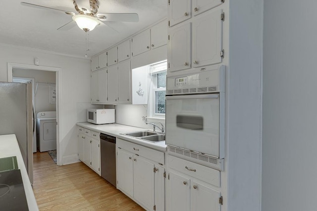 kitchen featuring appliances with stainless steel finishes, washer / clothes dryer, sink, and white cabinets