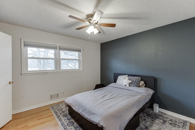 bedroom featuring ceiling fan, light hardwood / wood-style flooring, and a textured ceiling