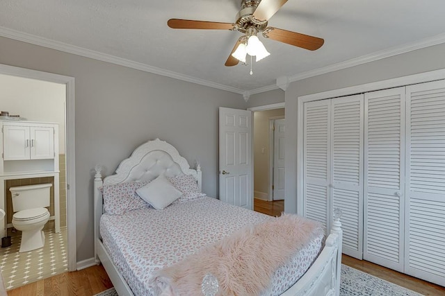 bedroom featuring crown molding, ensuite bath, ceiling fan, a closet, and light wood-type flooring