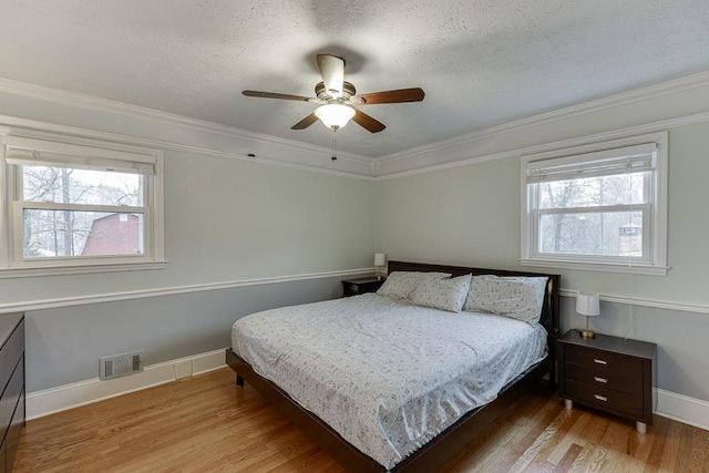 bedroom featuring wood-type flooring, ceiling fan, a textured ceiling, and crown molding