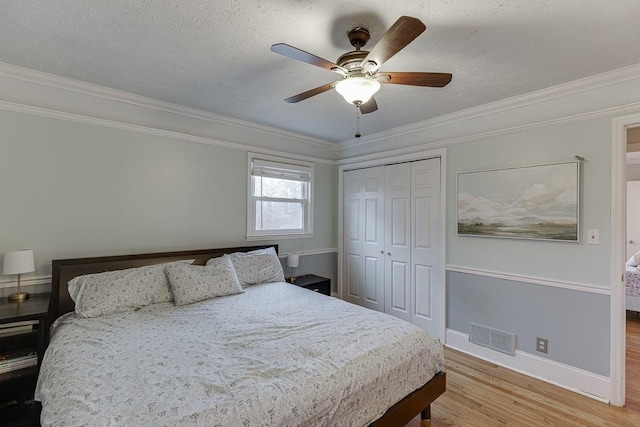 bedroom with ceiling fan, ornamental molding, a textured ceiling, a closet, and light wood-type flooring