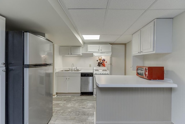 kitchen featuring sink, kitchen peninsula, white cabinets, and appliances with stainless steel finishes