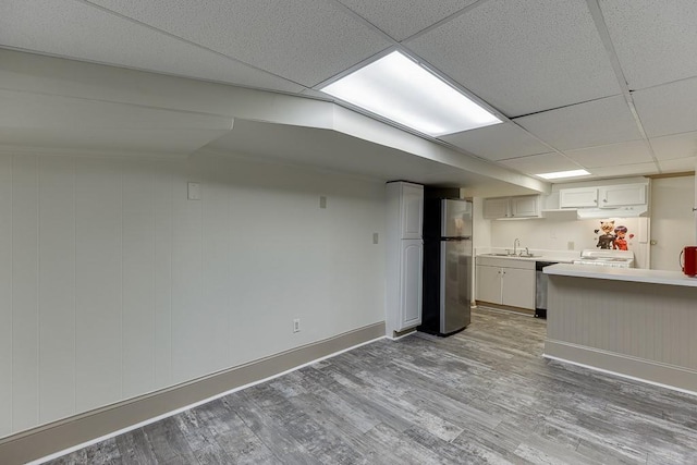 kitchen featuring sink, white cabinetry, wood-type flooring, stainless steel appliances, and a drop ceiling