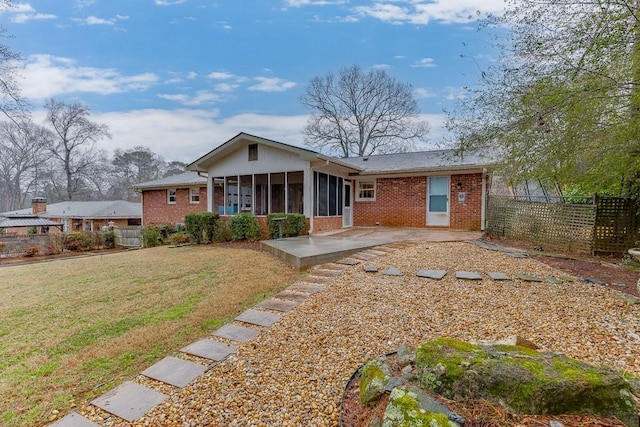 rear view of house featuring a lawn, a sunroom, and a patio