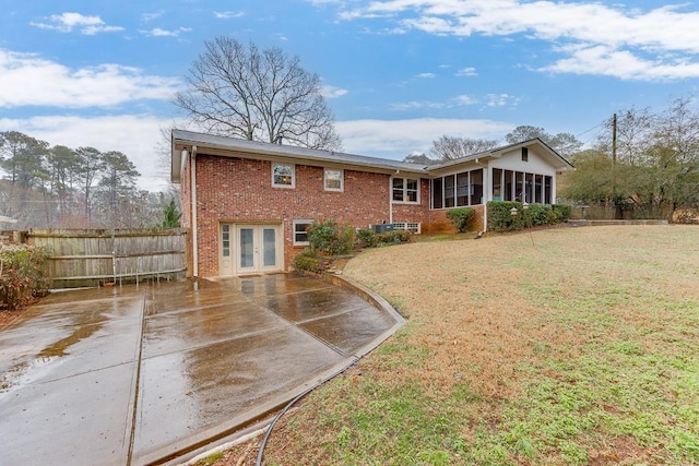 back of house featuring french doors, a patio, a sunroom, and a lawn