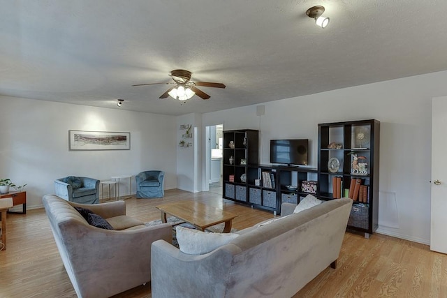 living room featuring a textured ceiling, ceiling fan, and light wood-type flooring