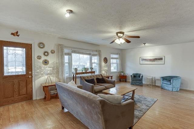 living room featuring ceiling fan, a textured ceiling, and light wood-type flooring