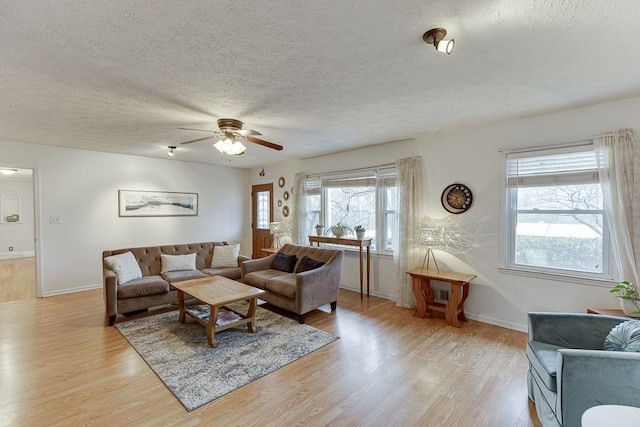 living room with ceiling fan, light hardwood / wood-style flooring, and a textured ceiling