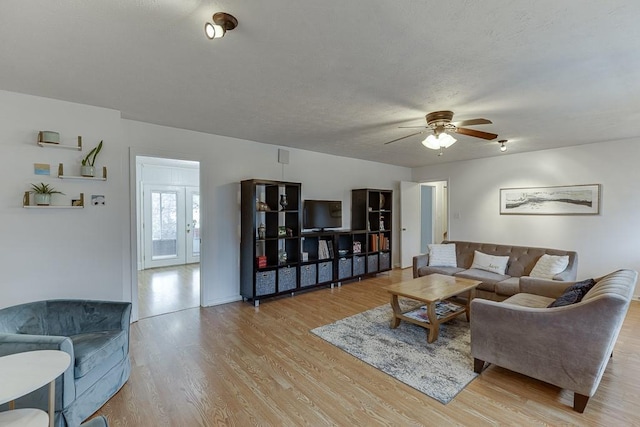 living room featuring ceiling fan, a textured ceiling, and light wood-type flooring